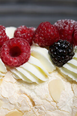 Meringue roll with mascarpone cream. Garnished with raspberries and almond petals. Close-up.