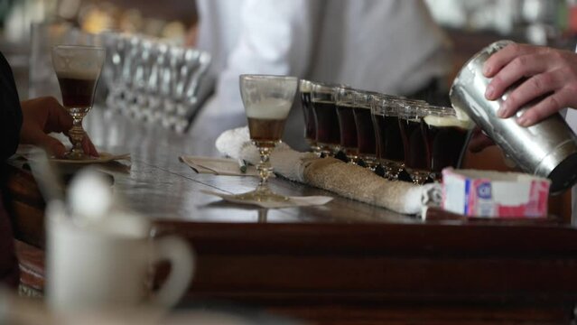 This video shows a row of Irish Coffee cocktails being made at old bar counter.