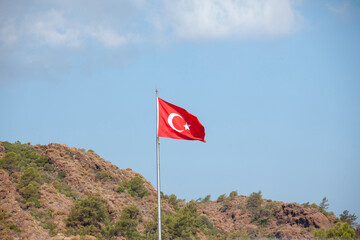 Turkish flag waving in blue sky against mountain, Turkey. Turkey flag on a flagpole.