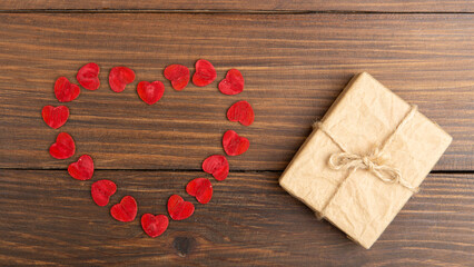 Valentine's Day greetings concept. Little red wooden crafted hearts and gift boxes on the wooden background. Valentines greeting card.