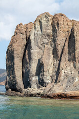 Stone cliff in Aegean sea. High rock in the sea. View from sea. Rock reflection in blue water sea