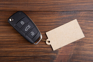 Car insurance or rent concept. Vehicle security key with blank tag on the wooden background - 529220625