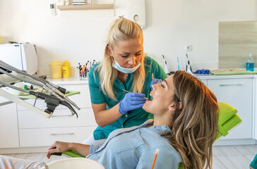 Female dentist examining a patient's teeth in the dentist office.	
