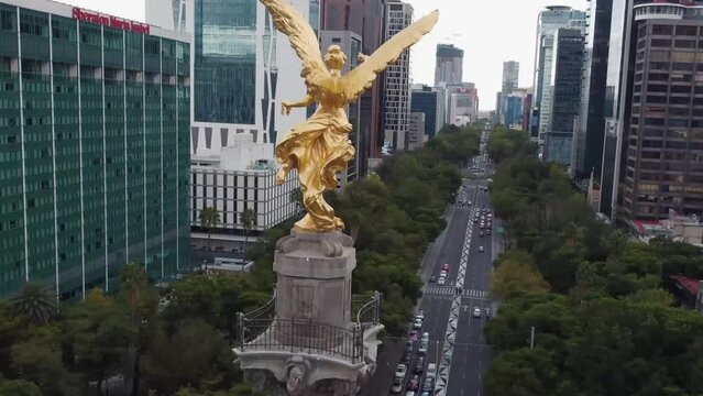 Aerial video of the Angel de la Independencia and the buildings around it on a cloudy day in the Paseo de la Reforma in Mexico City