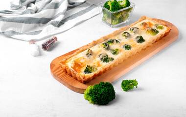 Broccoli and cheese tart of rectangular shape on shortbread dough on the white table. Savory pie