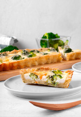 Piece of broccoli tart on shortbread dough on the white table. Savory pie