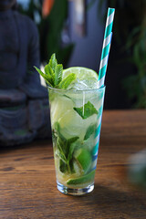 Mojito drink. Cocktail based on rum, mint, brown cane sugar, lime and crushed ice in a long glass, on a wooden table.