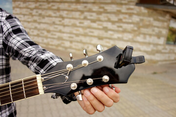 hand of man guitarist tuning the guitar strings