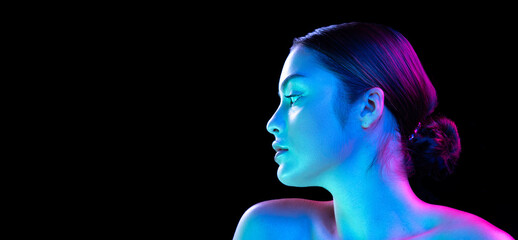 Flyer with young fashion model without makeup looking at camera isolated over dark background in neon light. Concept of beauty, art