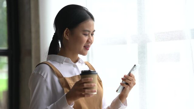 Happy asian woman in apron working at coffee shop.