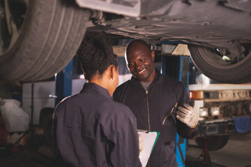 African american  Two mechanics - man examining car engine. Auto mechanic working in garage.Car Mechanic Detailed Vehicle Inspection. Auto Service Center Theme.