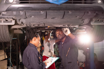African american  Two mechanics - man examining car engine. Auto mechanic working in garage.Car Mechanic Detailed Vehicle Inspection. Auto Service Center Theme.