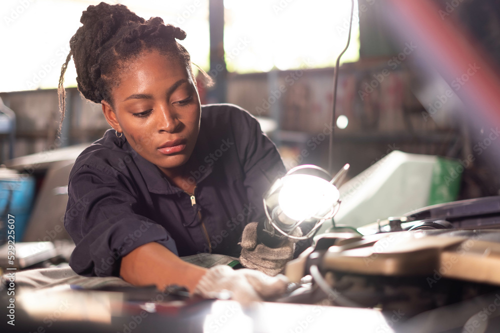 Poster African american technician female Mechanic working under the hood at the repair garage.