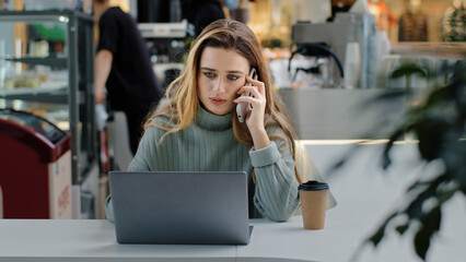 Serious business woman freelance manager worker student sitting at table with laptop answering call...