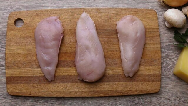 Chicken fillet chicken breast lies on a cutting board on the kitchen table.