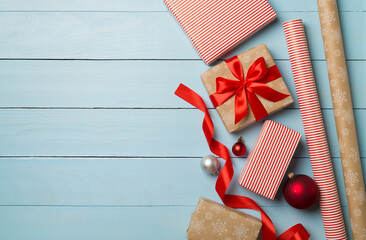 Gift boxes, paper's rools and decorations on wooden background, top view