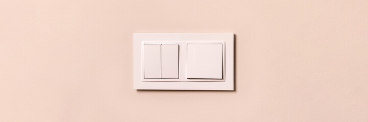 Group of white electrical switches on modern beige wall with copy space banner. Wide panoramic...