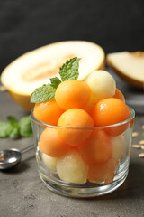 Melon balls and mint in glass on grey table, closeup