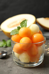 Melon balls and mint in glass on grey table, closeup