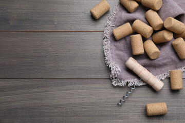 Corkscrew and wine bottle stoppers with napkin on wooden table, flat lay. Space for text