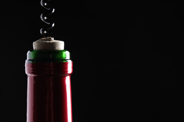 Opening wine bottle with corkscrew on dark background, closeup. Space for text
