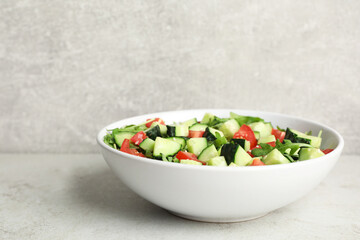 Delicious salad with cucumbers, tomatoes and sesame in bowl on light table, space for text