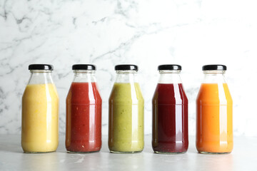 Bottles with delicious colorful juices on marble table