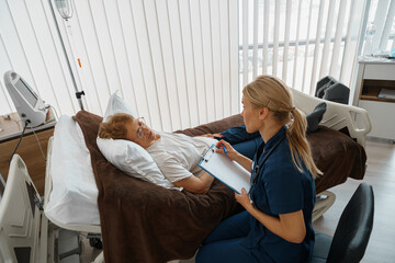 Professional doctor in uniform examines the patient during a visit to hospital ward in clinic