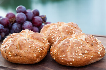Buns with sesame and grape on cutting board.