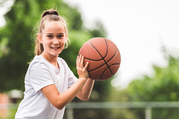 portrait of a kid girl playing with a basketball in park