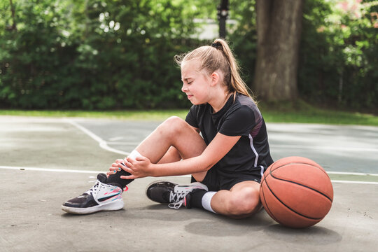 girl with basketball on court on summer season having hurt