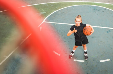 portrait of a kid girl playing with a basketball in park