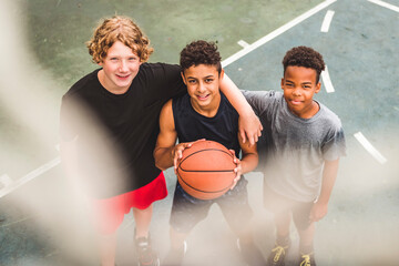 Three teens in sportswear playing basketball game