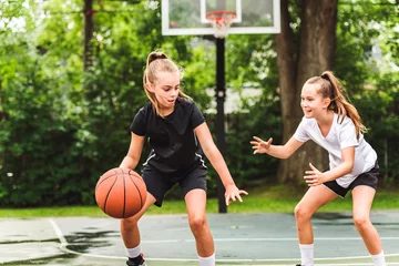 Foto op Plexiglas two girl child in sportswear playing basketball game © Louis-Photo