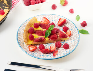 Round quiche with red strawberries and raspberries on a white table