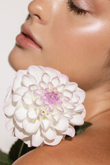 Obraz na płótnie Canvas Beauty portrait of charming young girl with flower isolated over white studio background. Cosmetics, natural beauty and aesthetic cosmetology concept.