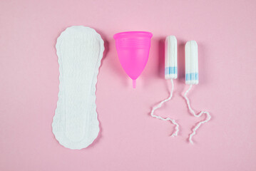 women's tampons, menstrual cup, pads on a pink background. Feminine hygiene. Menstruation.