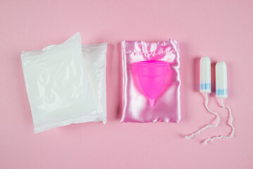 women's tampons, menstrual cup, pads on a pink background. Feminine hygiene. Menstruation.