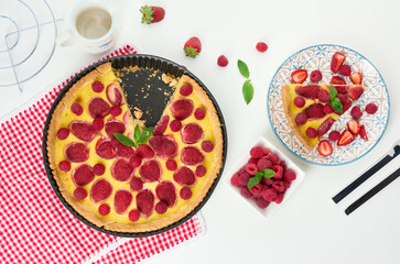 Round quiche with red strawberries and raspberries on a white table