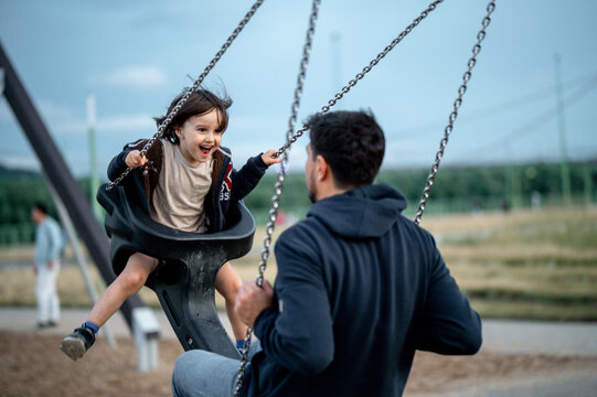 Dad and son swing on a swing. Happy family. The father spends time with the children, the father walks with the child in the summer in the park