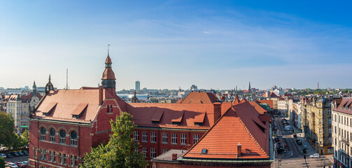 Fototapeta na wymiar Panorama of the city of Katowice. In the foreground there is a historic school building in the neo-Gothic style with red tiled roofs. Katowice, Poland