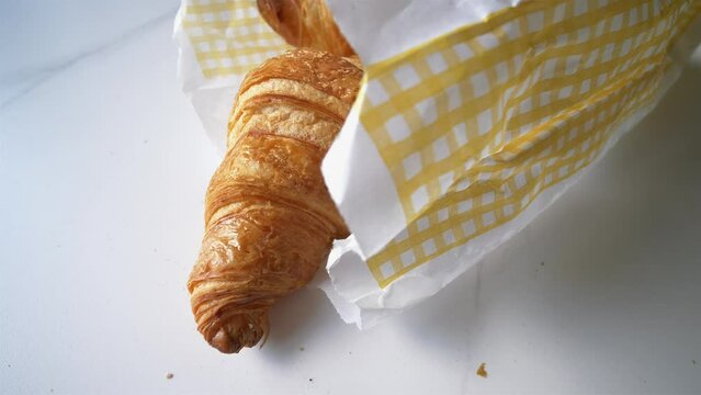 Croissant in paper bag on marble kitchen top