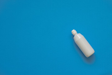 On a blue background, a bottle with a solution. Lens solution. Soft focus