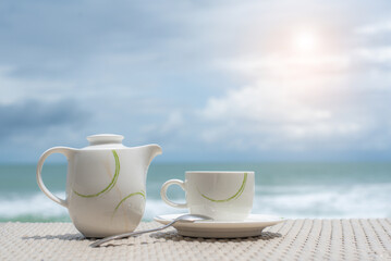 cup and pot of tea on wood table sea background.