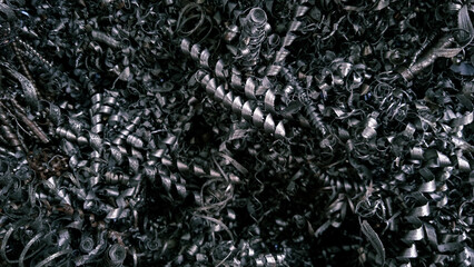 Steel scrap materials recycling. Aluminum chip waste after machining metal parts on a cnc lathe. Closeup twisted spiral steel shavings. Small roughness sharpness, possible granularity, blurred focus

