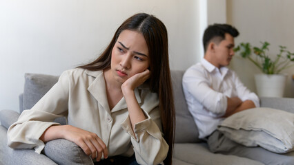 Young couple relation problem concept : Young Asian woman feeling sad and crying after have an argument at home. Sad or depressed woman sitting on sofa with her couple.