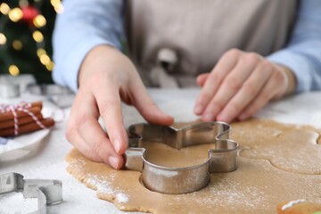 Woman making Christmas gingerbread man cookies at white table, closeup