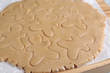 Making homemade Christmas cookies. Dough for gingerbread men on wooden board, closeup