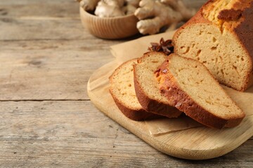 Sliced delicious gingerbread cake on wooden table, space for text