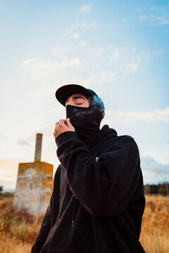 Guy with balaclava smoking a joint of marijuana outdoors